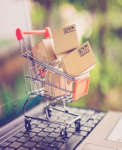 Online shopping and delivery service concept. Paper cartons in a shopping cart on a laptop keyboard, this image implies online shopping that customer order things from retailer sites via the internet.