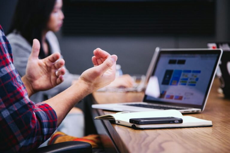 Two colleagues reviewing a marketing analytics dashboard on a laptop while discussing B2B SaaS campaign attribution during a meeting