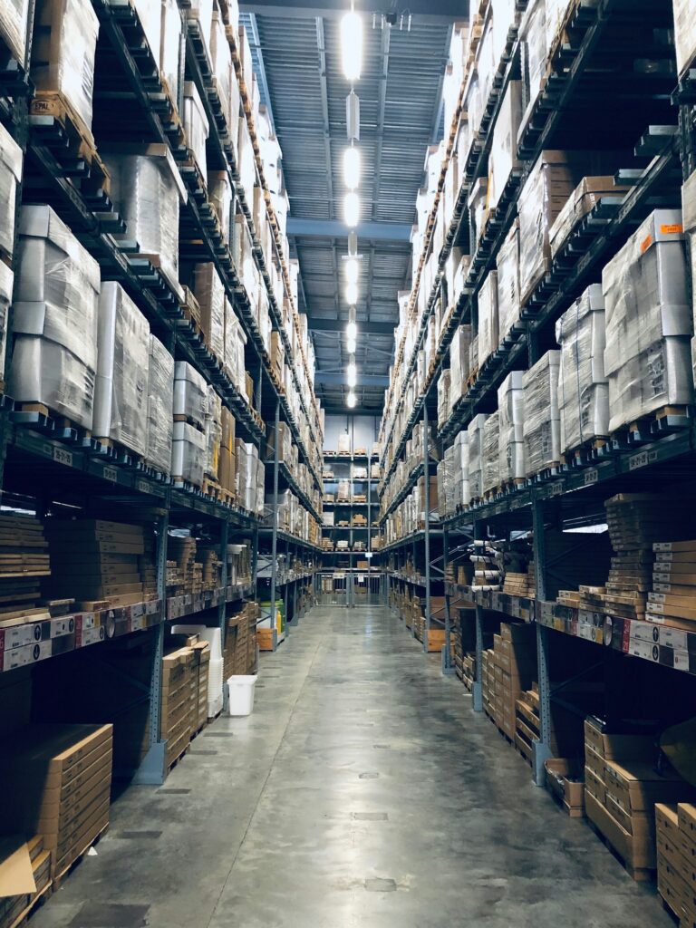 Warehouse aisle with racked, wrapped pallets representing retail merchandising and inventory allocation software
